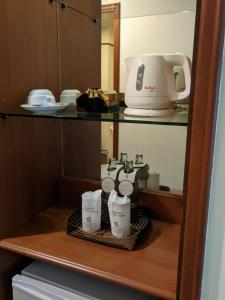 a cabinet with a coffee maker and cups on a shelf at โรงแรม ซี.เอส. ปัตตานี in Ban Ru Sa Mi Lae