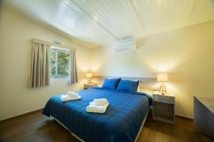 1 dormitorio con 1 cama azul y 2 toallas en Vista Alegre Natural Resort - Bungalows, en Independencia