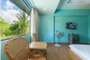 a bedroom with a window and a bed and a table and chairs at Amaia Homestay - a beach home away from home in Phú Quốc