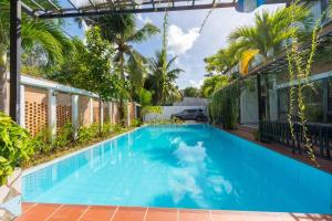 a large blue swimming pool in a yard with palm trees at Amaia Homestay - a beach home away from home in Phú Quốc