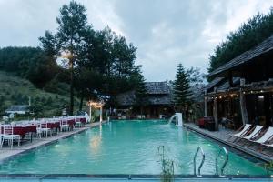 a large swimming pool with chairs and a building at The Nordic Village - Evergreen Retreat in Mộc Châu