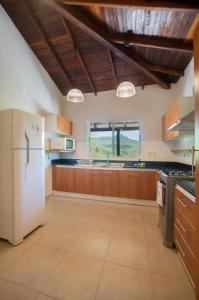 a kitchen with a white refrigerator and wooden cabinets at Vista Alegre Natural Resort - Villas & Cabañas in Independencia
