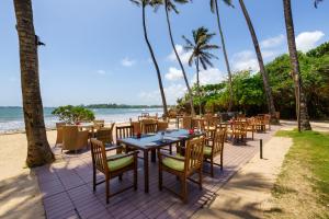 a restaurant on the beach with tables and chairs at Cocobay Unawatuna in Unawatuna