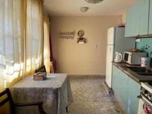 Una pequeña cocina con una mesa y un refrigerador. en Casa Rosa, en Alta Gracia