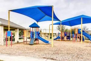 um parque infantil com guarda-sóis azuis e escorregas em “Casa Linda” Relaxing stay in a friendly community em San Antonio