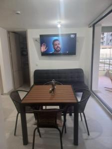 een tafel en stoelen met een tv aan de muur bij Apartamento cómodo con todo lo que necesitas y con piscina in Ricaurte