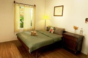 Vườn Nhà Ngoại Garden Homestay في Cu Chi: وجود دبدوب يجلس على سرير في غرفة النوم