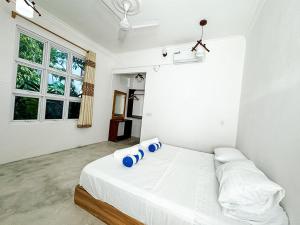 a bedroom with a white bed with blue pillows on it at Ithaa Hiya Dhihfushi in Dhiffushi