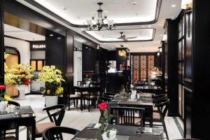 a restaurant with black tables and chairs and flowers at PALAGO BOUTIQUE HOTEL in Hanoi