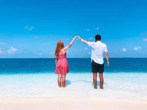 a man and a woman standing on a beach at iCom Marina Sea View in Maafushi
