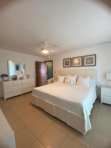a bedroom with a large white bed and a mirror at Majestuoso Apto. en el Complejo Marbella, Juan Dolio in Juan Pedro