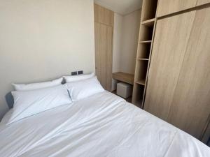 1 dormitorio con cama blanca y estante para libros en 2 Bedroom Luxury Apartment 3 min walk from BTS Ekkamai en Bangkok