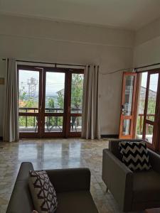 een woonkamer met een bank en grote ramen bij Bukit Jaya Residence & Apartment Semarang in Semarang