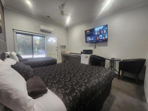 a bedroom with a bed and a flat screen tv at Motel24Seven and Apartments in Sale