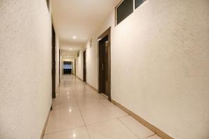 un corridoio con pareti bianche, pavimenti piastrellati e una porta di FabHotel Neena Palace a Bhopal