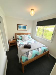 Un dormitorio con una cama grande con ventana. en Tidal Dreaming Seaview Cottages, en Yanakie
