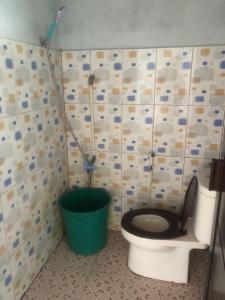 a bathroom with a toilet and a green bucket at Yenkoranu Homestay and Dive Center in Waisai