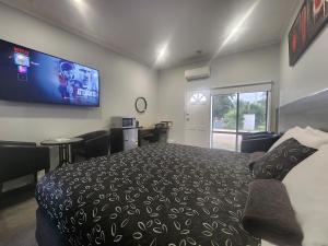 a bedroom with a bed and a tv on the wall at Motel24Seven and Apartments in Sale