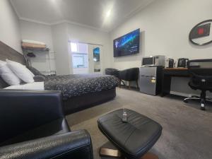 ein Schlafzimmer mit einem Bett, einem Schreibtisch und einem Sofa in der Unterkunft Motel24Seven and Apartments in Sale