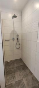 ein Bad mit einer Dusche und weißen Fliesenwänden in der Unterkunft Ferienwohnung M. König in Radolfzell am Bodensee