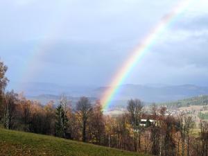 a rainbow in the sky with a field and trees at Apartmány u Pilaře in Majdalena
