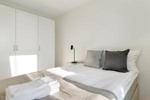 - une chambre dotée d'un grand lit avec des draps blancs et des oreillers gris dans l'établissement Guestly Homes - 1BR Corporate Comfort, à Boden