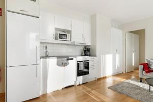 a white kitchen with white cabinets and appliances at Guestly Homes - 1BR Corporate Comfort in Boden