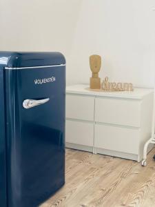 un frigorifero blu seduto accanto a un comò bianco di cozy Apartment/WLAN in Neustadt i. Sachsen a Neustadt in Sachsen