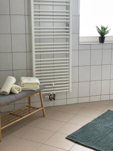 un bagno con pareti bianche piastrellate e una panca con asciugamani di cozy Apartment/WLAN in Neustadt i. Sachsen a Neustadt in Sachsen