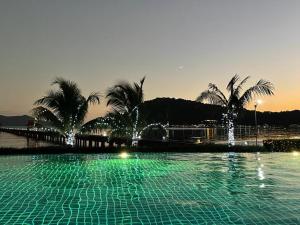 a swimming pool with a fountain and palm trees at Panoramic sea view, 1 bed flat in Ban Bang Bao