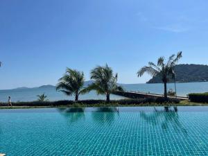 a swimming pool with palm trees and the water at Panoramic sea view, 1 bed flat in Ban Bang Bao