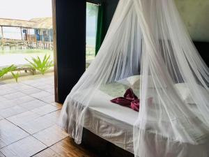 a bed with a mosquito net in a room at Yenkoranu Homestay and Dive Center in Waisai