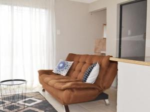 a living room with a brown couch and a table at Karaboapartlodge in Jane Furse