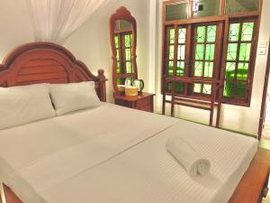 a bedroom with a large white bed with a wooden headboard at Walawa Blue Sapphire in Udawalawe