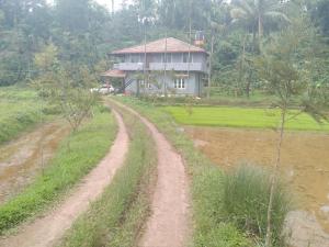 un chemin de terre devant une maison dans un champ dans l'établissement Samz estate stay 2BHK, à Madikeri