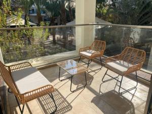three rattan chairs and a table on a balcony at Beach Apartment - Ramat Aviv in Tel Aviv