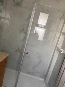 y baño con ducha y puerta de cristal. en Beach Apartment - Ramat Aviv en Tel Aviv