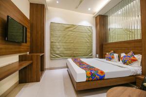 Dormitorio pequeño con cama y TV en FabHotel Royal Palace II, en Bhopal