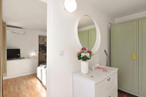 une chambre avec un vase de fleurs sur une commode avec un miroir dans l'établissement Apartment View And Pool - Happy Rentals, à Agno