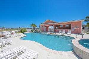 a swimming pool with white chairs and a building at By Air & By Sea in Port Aransas