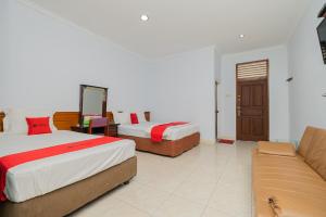 a hotel room with two beds and a couch at RedDoorz near Bojonegoro Train Station in Bojonegoro