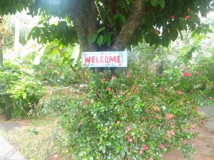 a welcome sign in a garden with flowers at Gigi's Self Catering Apartment in Port Glaud