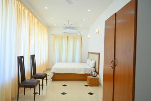 ein Hotelzimmer mit einem Bett und zwei Stühlen in der Unterkunft Villa Happiness in Puducherry