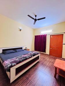 een slaapkamer met een bed en een plafondventilator bij SPM Residency, From Live2Travel Group. in Masinagudi