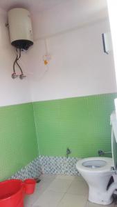 baño verde y blanco con aseo en Devtauli, en Almora