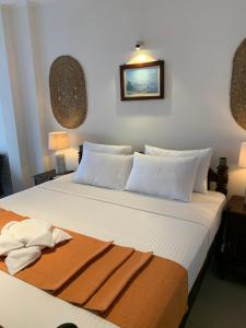 een slaapkamer met een groot bed met witte kussens bij Neevana Hotel Hikkaduwa in Hikkaduwa