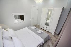 a white bedroom with a bed and a mirror at Апартаменты бизнес-класса в ЖК Amir in Almaty
