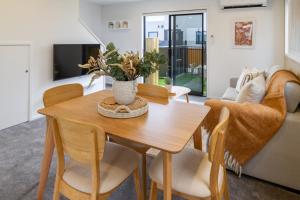 Una sala de estar con una mesa y sillas de madera. en New Brighton Beach Explore - King Bed and sofa bed, en Christchurch