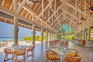a restaurant with tables and chairs and the beach at Emerald Faarufushi Resort & Spa - Deluxe All Inclusive in Raa Atoll