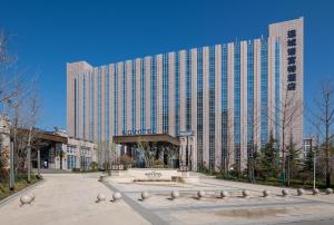 a large building with a fountain in front of it at Novotel Shanxi Yuncheng in Yuncheng